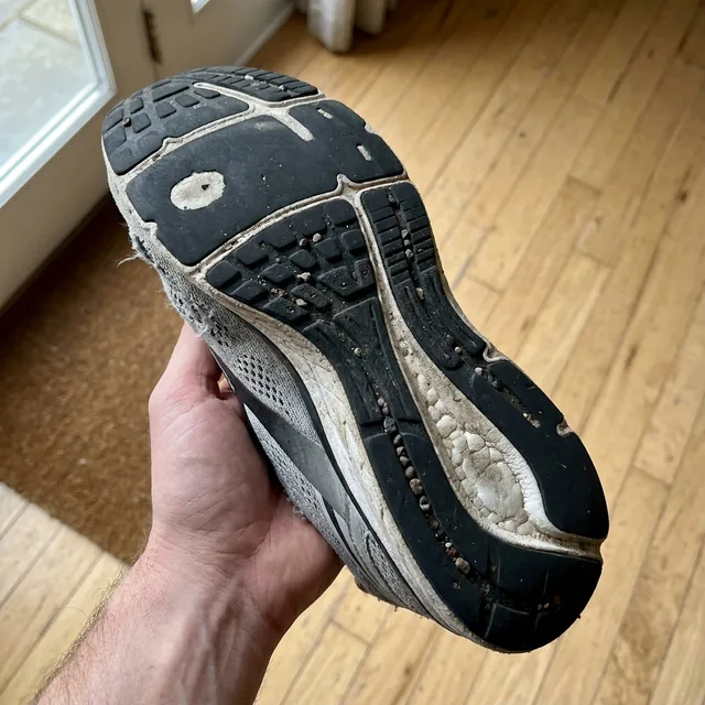 A worn running shoe outsole held up to the camera